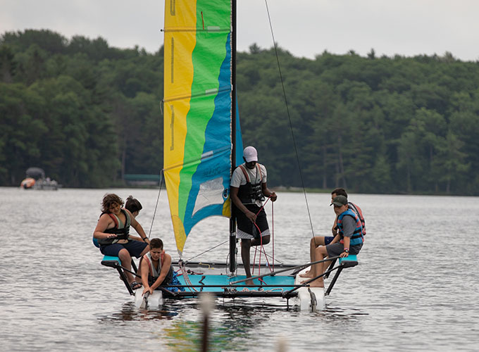 A group of campers and an instructor at North Star Camp for Boys steer a sailboat on Spider Lake.