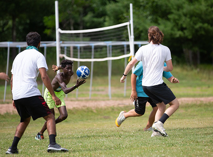 A camper holding a blue ball runs parallel to his opponents during a game of Speedball at North Star Camp for Boys.