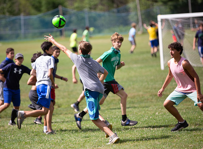 A camper runs for an airborne green ball while other campers run alongside him and watch his next move during a game of Speedball at North Star Camp for Boys.