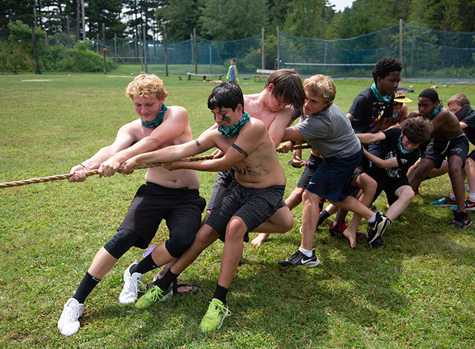 Campers wearing body paint and bandanas focus on pulling a rope for their team during a game of tug-of-war at North Star Camp for Boys.
