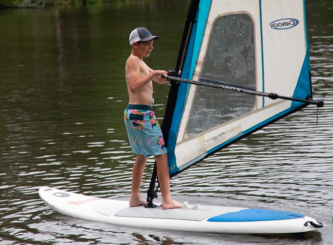A young camper at North Star Camp for Boys navigates a windsurf on Spider Lake in Hayward, Wisconsin.
