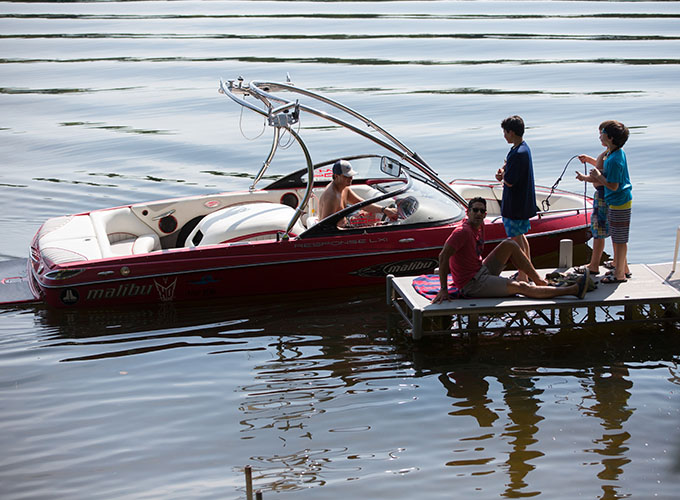 A staff member sits in a speedboat while three campers on the doc help prepare the anchor at North Star Camp for Boys.
