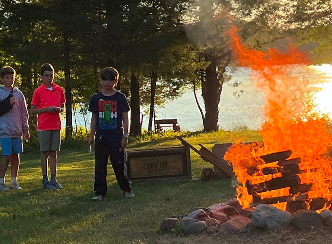 A group of campers watch a bonfire while participating in a Friday Night Service activity at North Star Camp for Boys.