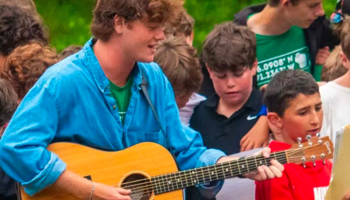 A camp counselor plays the guitar wile campers sing at North Star Camp for Boys.