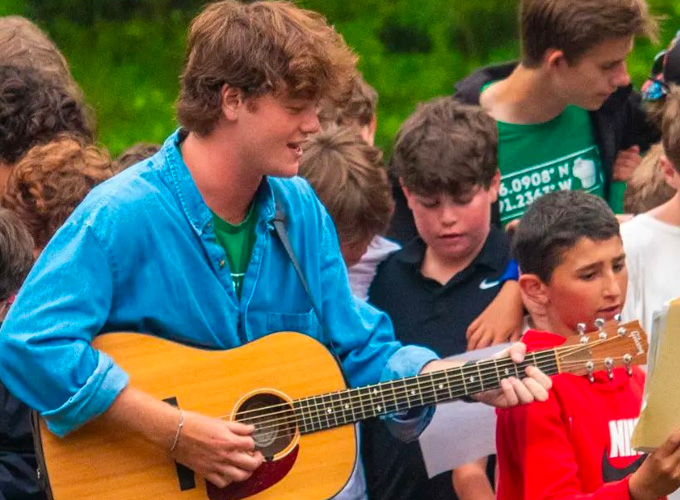 A camp counselor plays the guitar wile campers sing at North Star Camp for Boys.