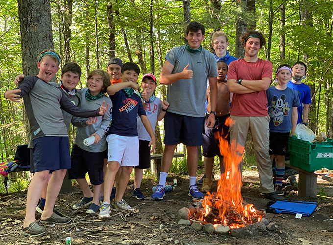 Campers celebrate as they stand around a campfire in the woods at North Star Camp for Boys.