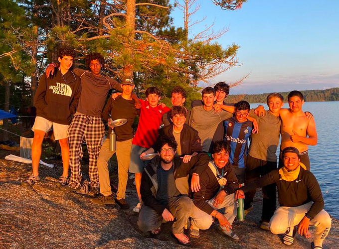 A group of campers and staff at North Star Camp for Boys smile for a picture on the lakeshore.