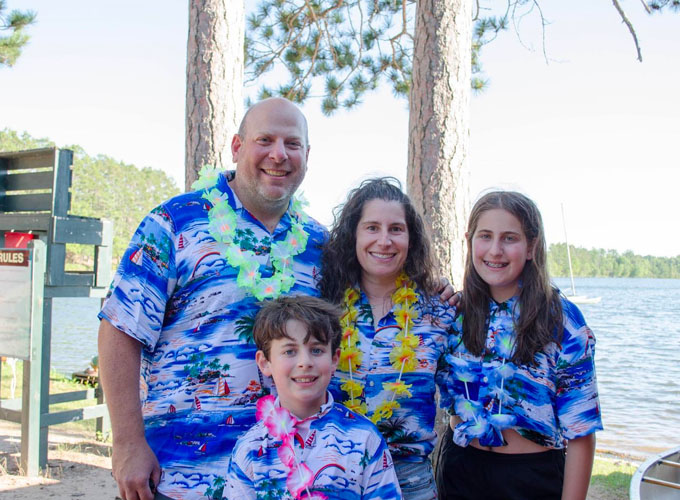 A family wears matching blue hawaiian shirts and leis at North Star Camp for Boys.