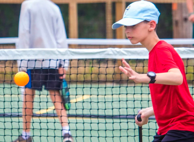 A camper prepares to hit a wiffleball during a game of pickleball at North Star Camp for Boys.