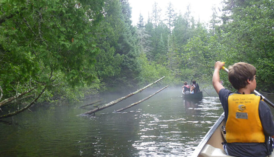 A camper wearing a lifejacket canoes through the river during a North Star Camp for Boys wilderness trip.