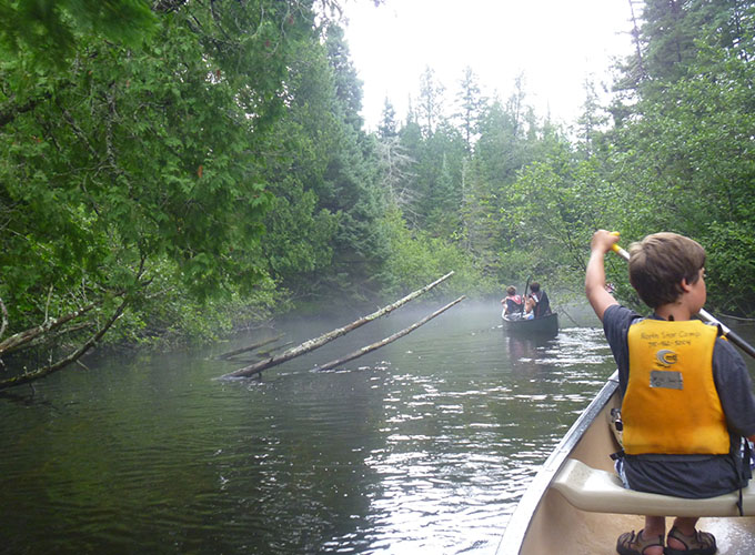A camper wearing a lifejacket canoes through the river during a North Star Camp for Boys wilderness trip.