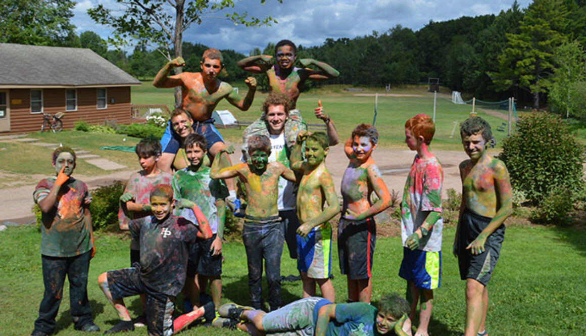 Campers wearing tie-dye body paint smile and pose during an activity at North Star Camp for Boys.