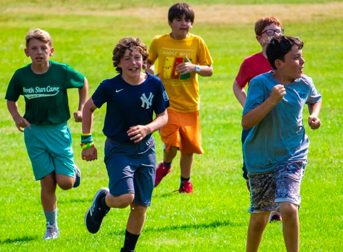 Campers run through a field during a cross country activity at North Star Camp for Boys.