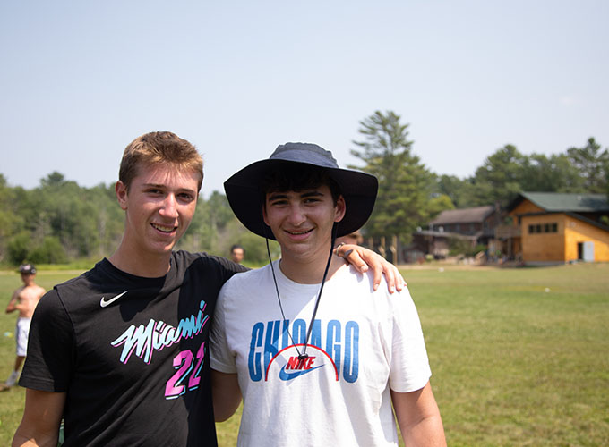 Two junior counselors at North Star Camp for Boys smile with their hands around each other.