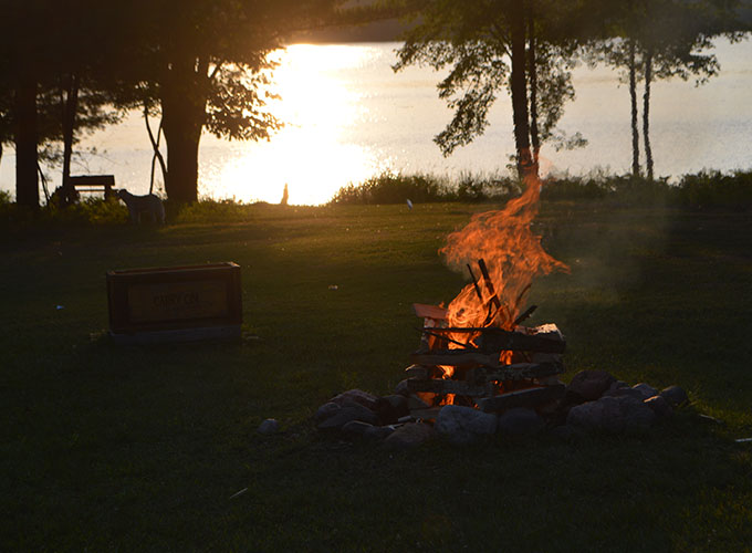 Bonfire burning near the lakeshore at sunset at North Star Camp for Boys.
