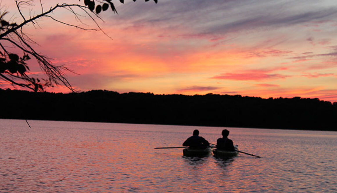 Two North Star Camp for Boys campers float down Spider Lake in canoes at sunset.
