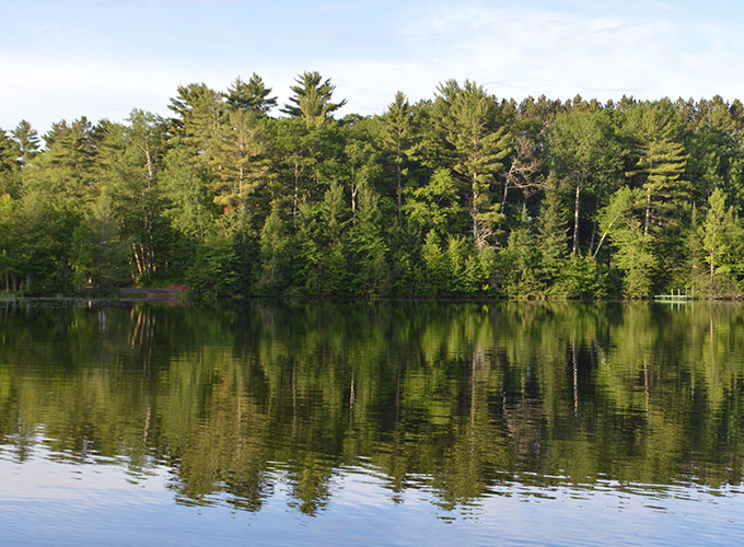 Scenic picture with lush trees reflecting the lake at North Star Camp for Boys.