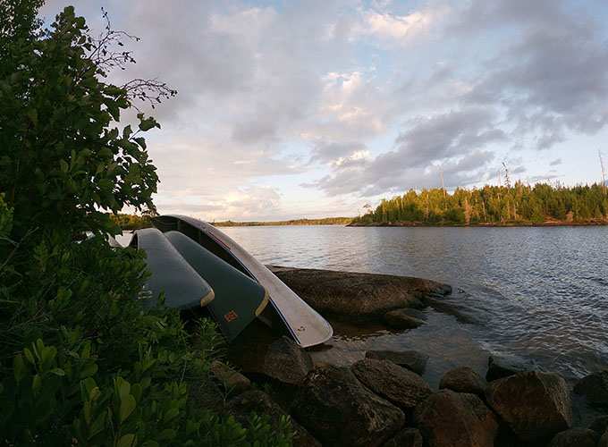 Canoes are stacked up against the shore of a lake during a wilderness trip for the campers and staff of North Star Camp for Boys.