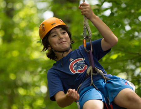 A camper holds back laughter while riding the zipline at North Star Camp for Boys.
