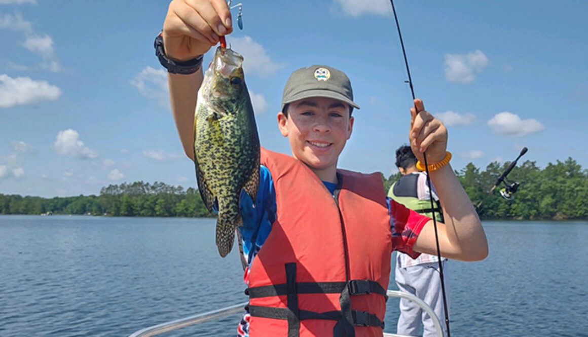 A camper poses while holding a fish he just caught at North Star Camp for Boys.