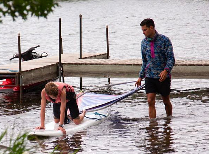A camper learns how to windsurf with the help of an instructor at North Star Camp for Boys.