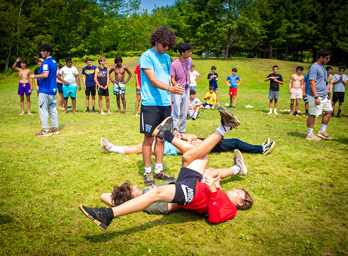 A group of boys compete in the college days activity at North Star Camp for Boys by doing a leg wrestling exercise.