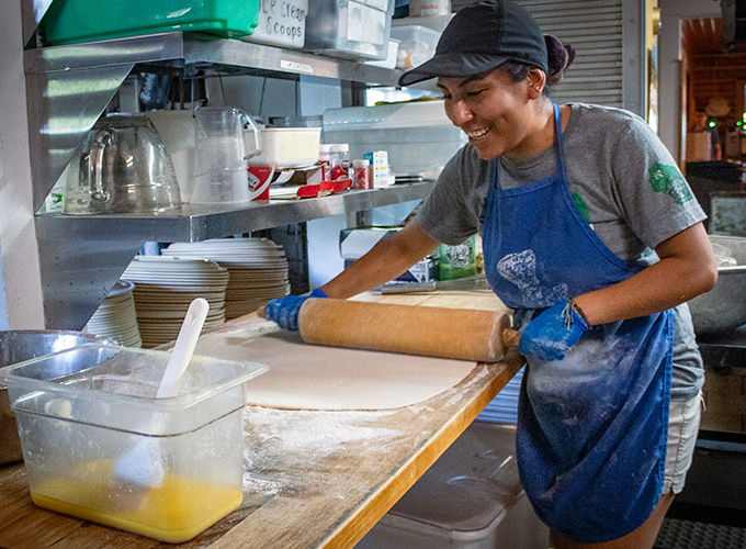 A kitchen staff member at North Star Camp for Boys rolls out homemade dough during meal prep.