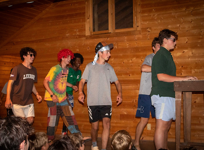 Campers at North Star Camp for Boys stand on stage in a log cabin while participating in a theatrical performance.