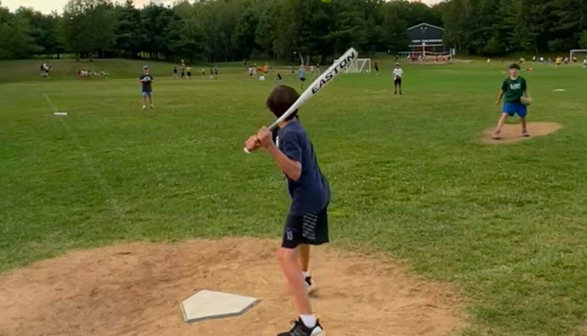 A camper prepares to hit an incoming softball while standing on home plate during a softball game at North Star Camp for Boys.