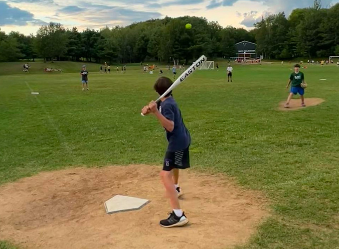 A camper prepares to hit an incoming softball while standing on home plate during a softball game at North Star Camp for Boys.