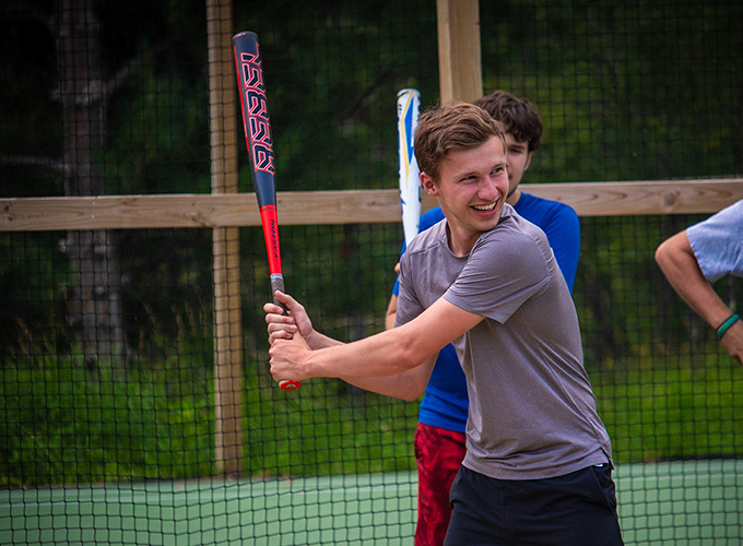 A camper smiles while practicing his softball bat swing at North Star Camp for Boys.