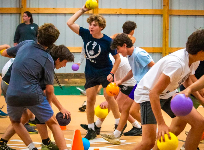 Campers in VICtory Fieldhouse at North Star Camp for Boys hold foam balls and aim to throw them during a game of dodgeball.