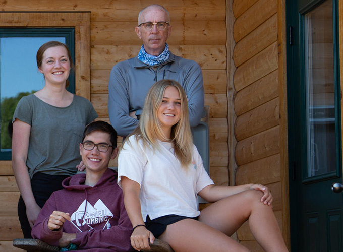 Four health staff members pose outside of a log cabin- the health center at North Star Camp for Boys.