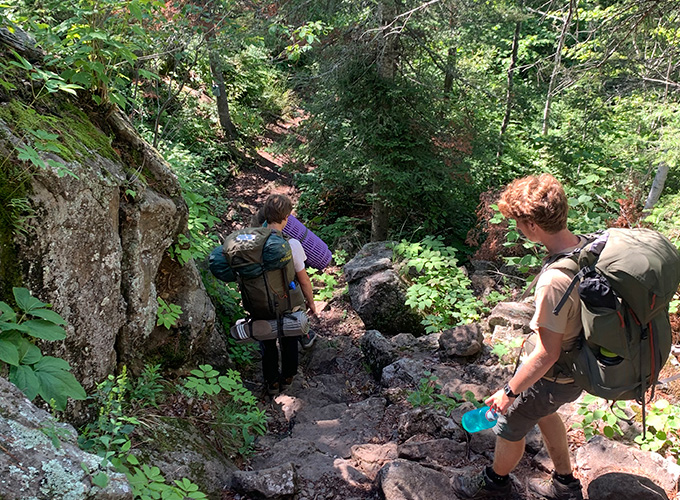 Campers navigate a rocky trail as they walk downward during a North Star Camp for Boys hiking trip.