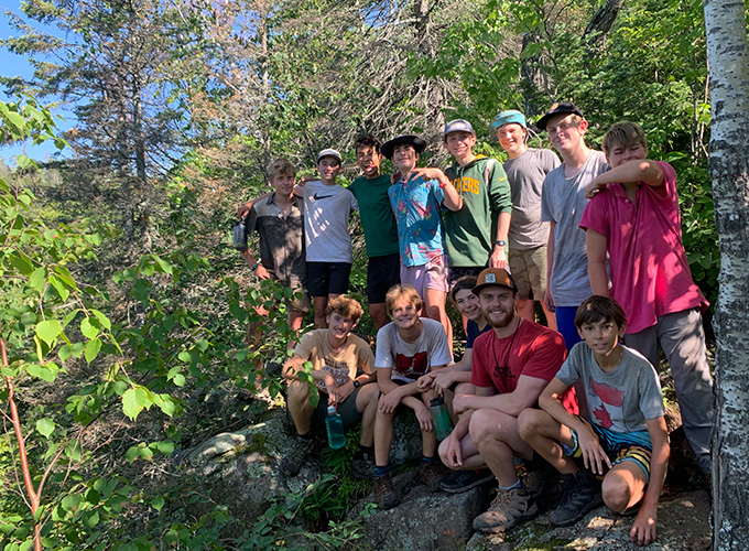 A group of campers and staff take a break and smile during a North Star Camp for Boys wilderness hiking trip.