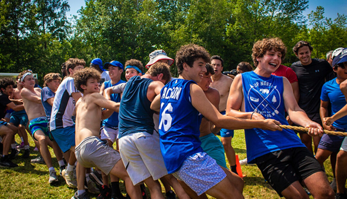 Campers laugh and smile while participating in a game of tug-of-war at North Star Camp for Boys.