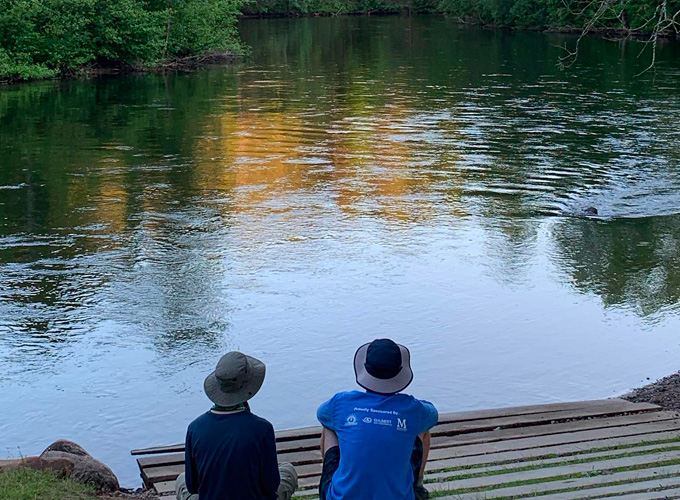 Two boys sit on a dock and look out at Namekagon River during a wilderness trip at North Star Camp for Boys.