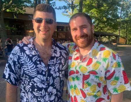 Two North Star alums wearing tropical clothing during a themed Happy Hour during Family Camp at North Star Camp For Boys.