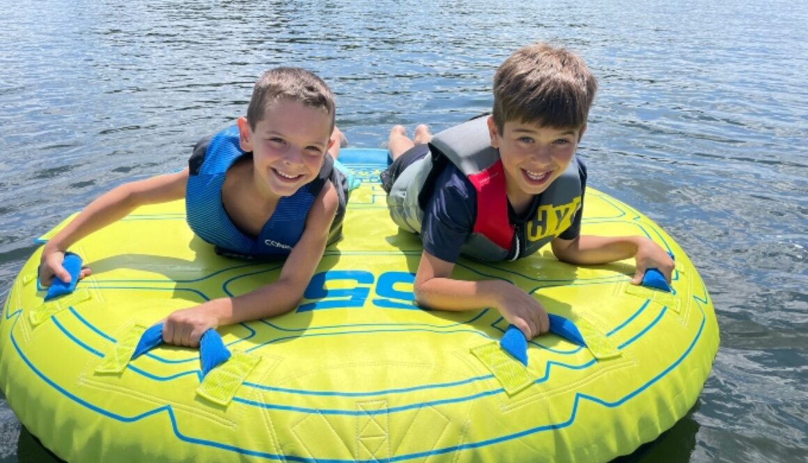 Two boys smile and get ready to go tubing during Family Camp at North Star Camp For Boys.