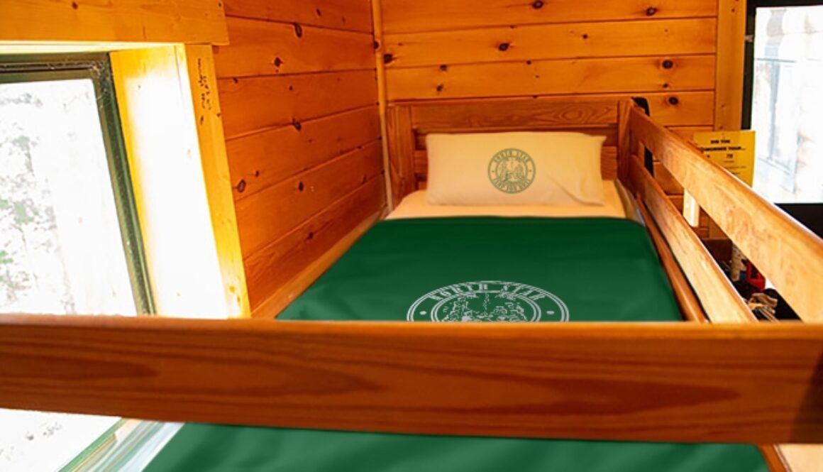 A bed made with blankets and pillows in a cabin at North Star Camp.