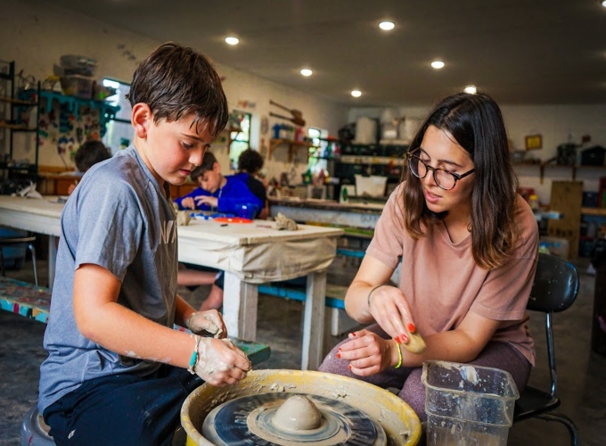 A camper at North Star Camp For Boys receives instructions on how to use a pottery wheel for his ceramic design.