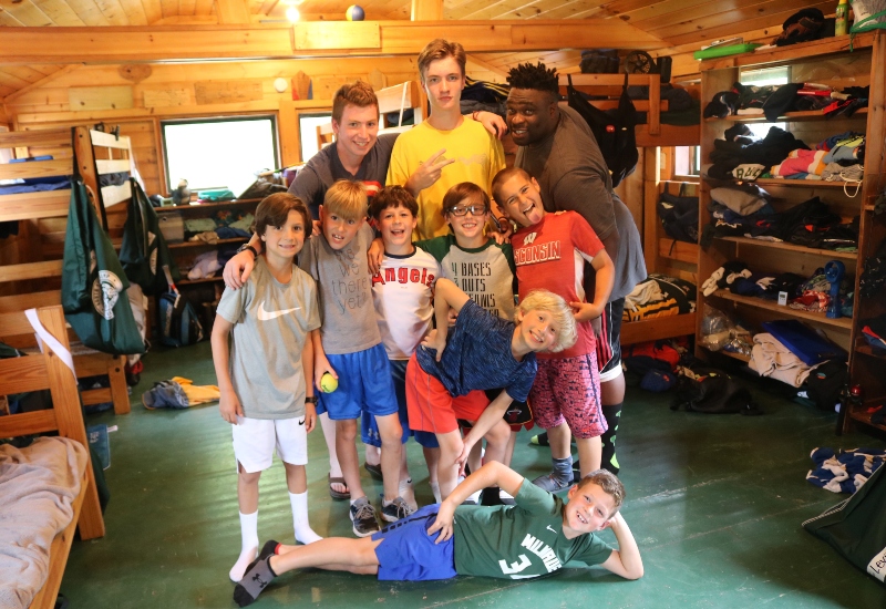 A group of campers and staff smile inside their cabin at North Star Camp For Boys.