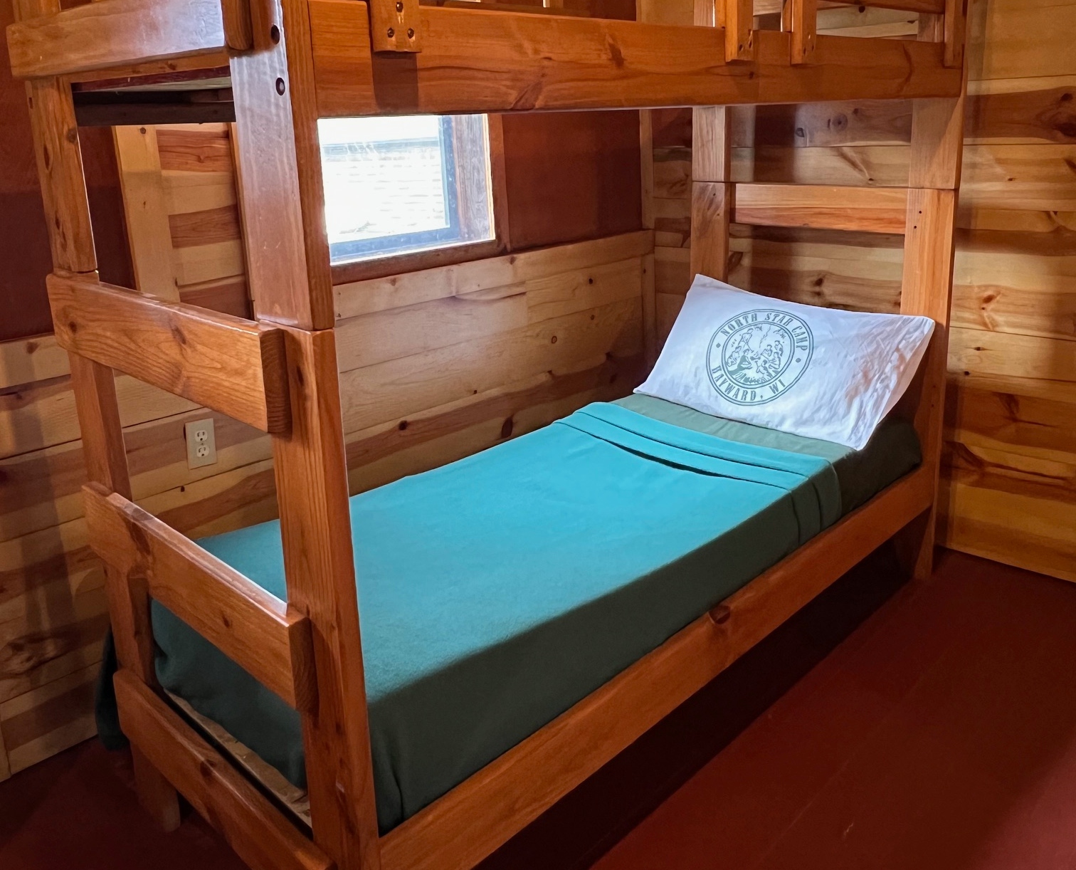 A camper's cabin bed made with North Star Camp bedding at summer camp