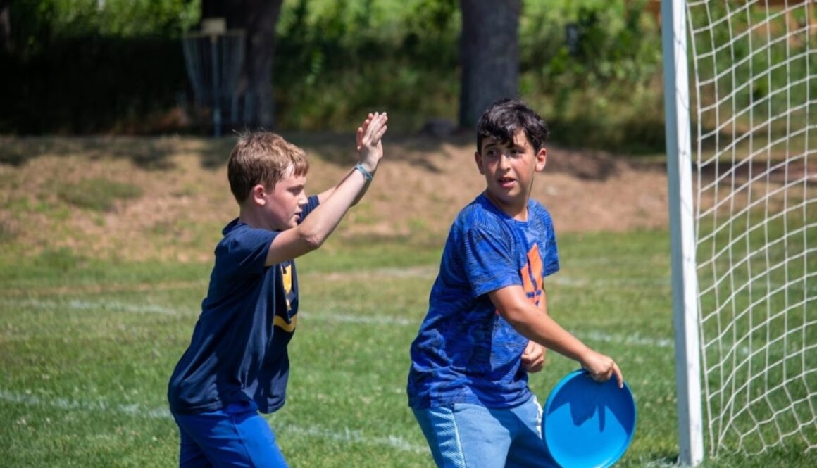 Two North Star Camp campers play a game of ultimate frisbee outside.