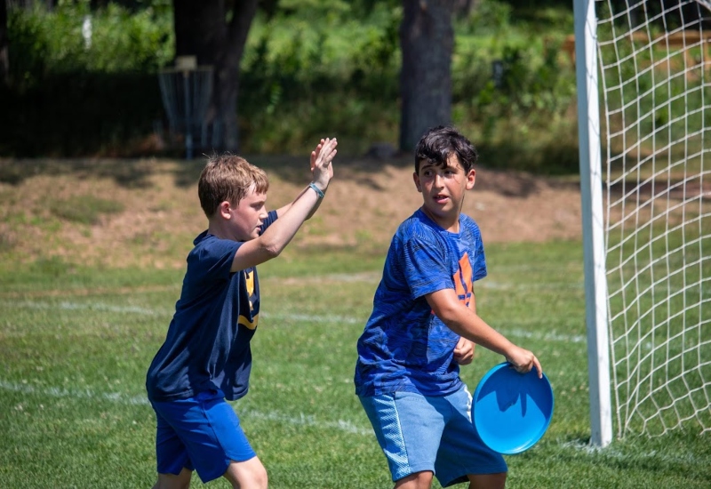 Two North Star Camp campers play a game of ultimate frisbee outside.