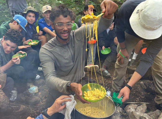 A North Star Camp wilderness trip leader makes a delicious dinner of mac and cheese on a camping trip with his campers.