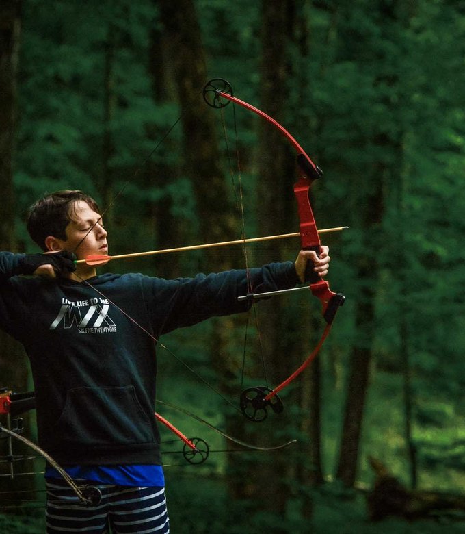 A camper draws a bow and takes aim at the archery range.