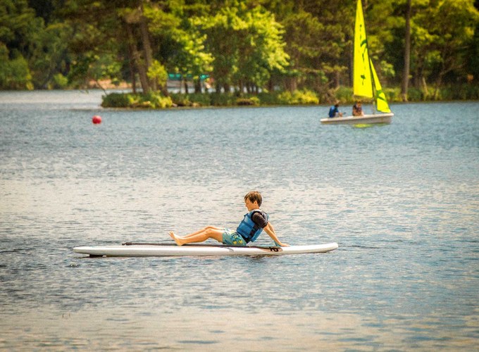 A camper paddles a stand up paddleboard across Spider Lake.