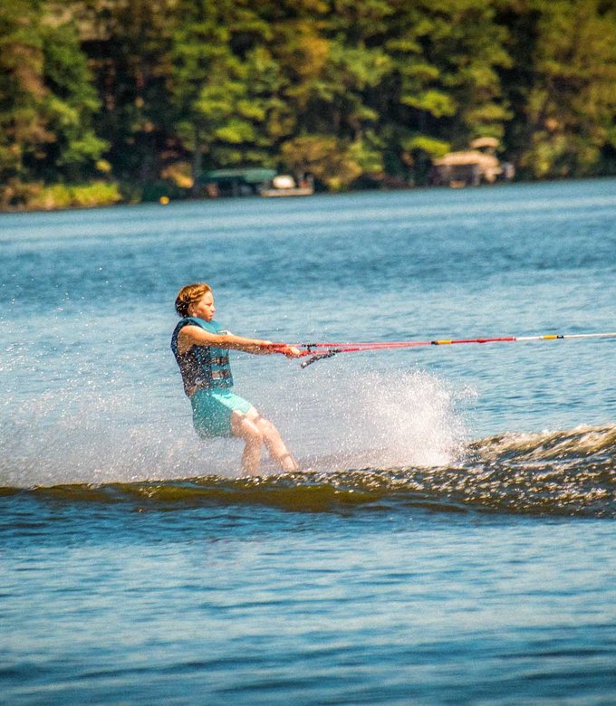 A camper waterskis across Spider Lake, spraying water behind him.