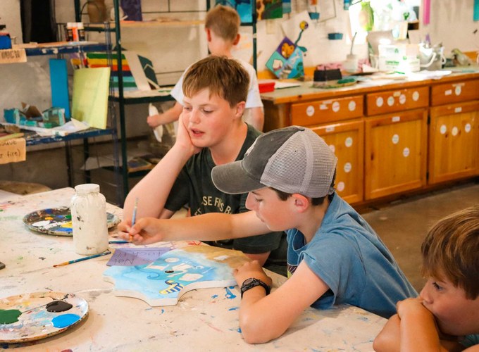 Campers paint at the arts and crafts tables.